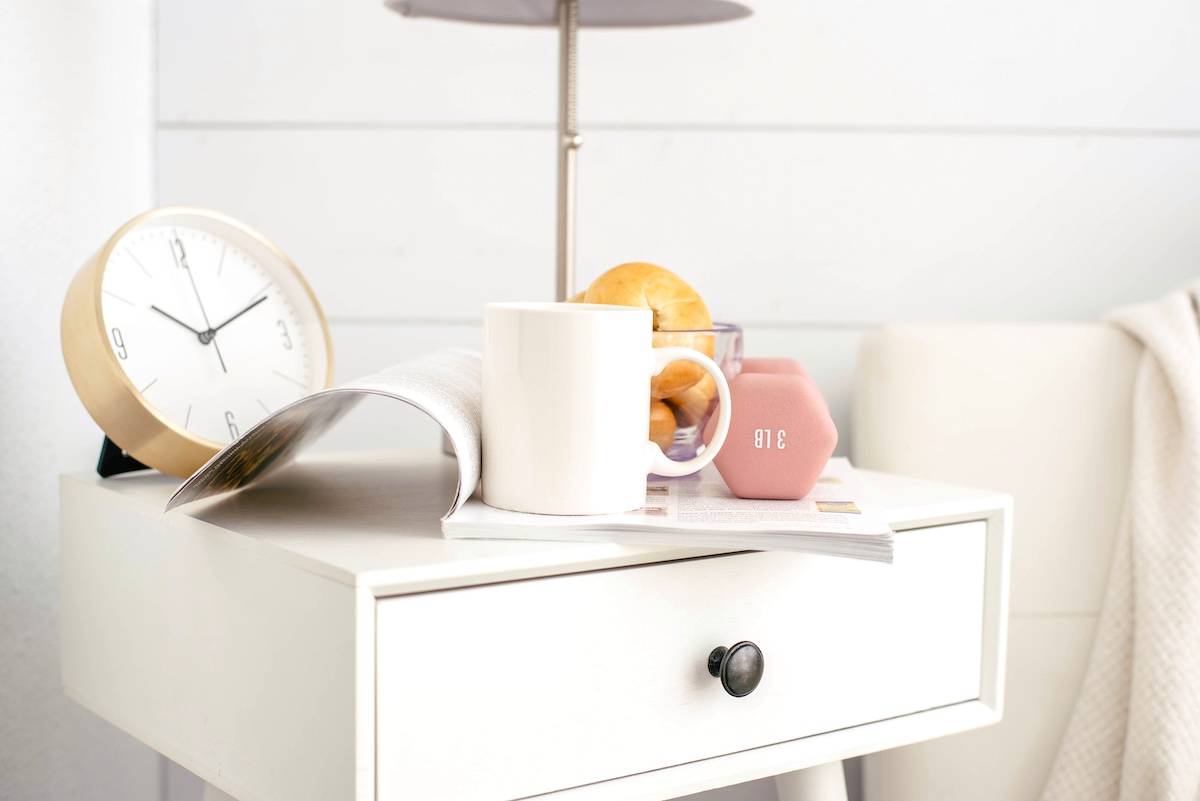 Bedside table, weight, bagels, clock, mug - items when thinking about the benefits of routines.
