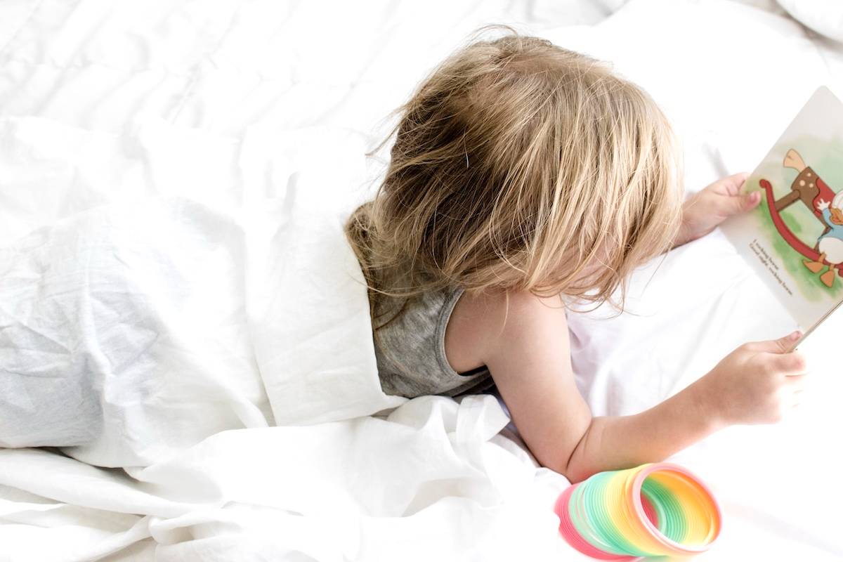 Girl reading in bed - a morning routine checklist.