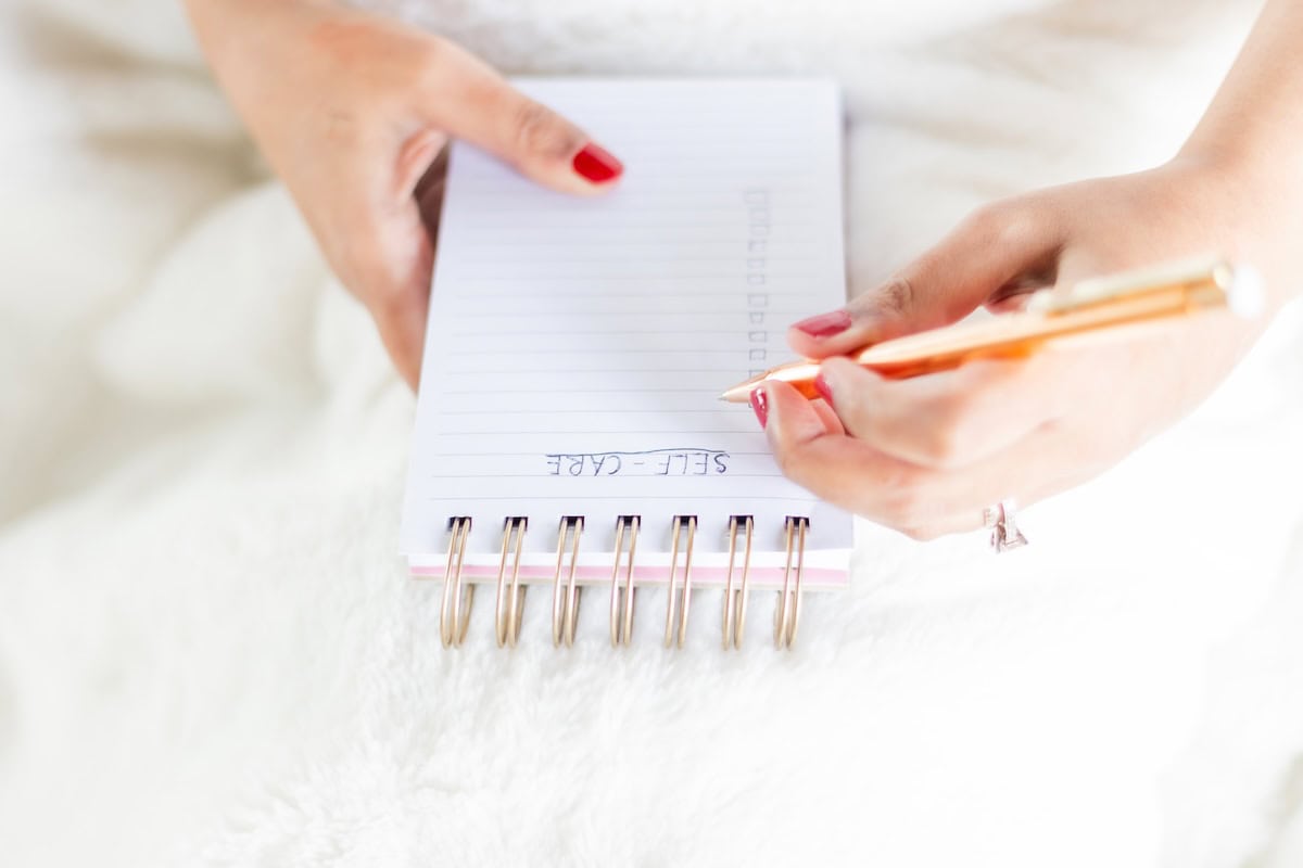 Woman writing self care list - self care routine ideas.