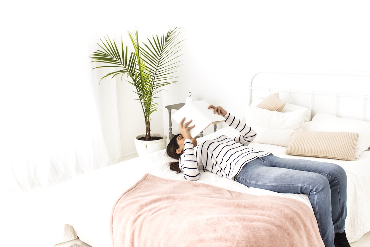 Woman laying on bed - tips for a bedroom declutter.