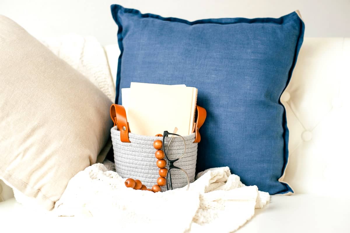 Sofa with cushions, basket holding paperwork - decluttered living room tips.