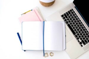 Computer and notepad on desk - paper planner and Google Calendar.