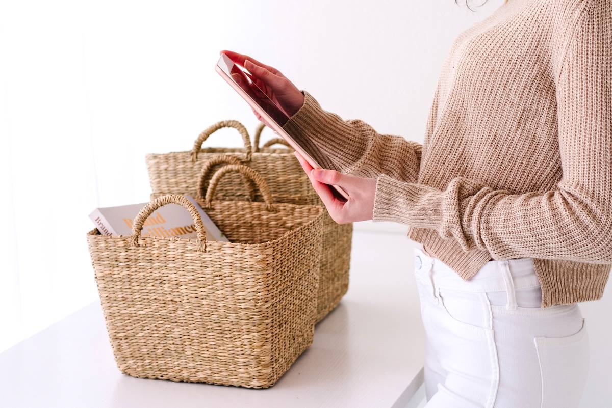 Women putting tablet into wicker basket - declutter checklist.