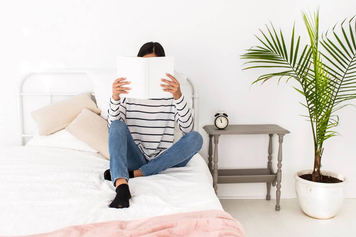 Woman reading on bed - ways to create a simpler home.