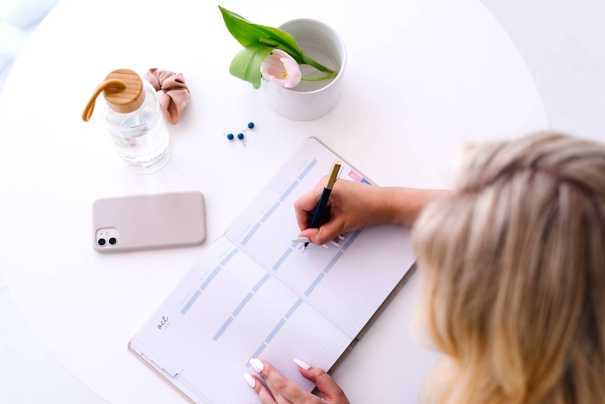 Woman writing in planner - ideas for a weekly family routine.