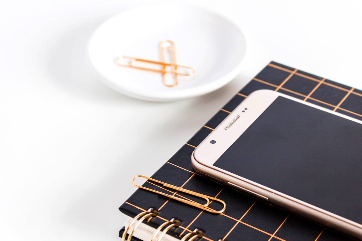 Paperclip, phone, stationery - items to help decide how to choose a planner.