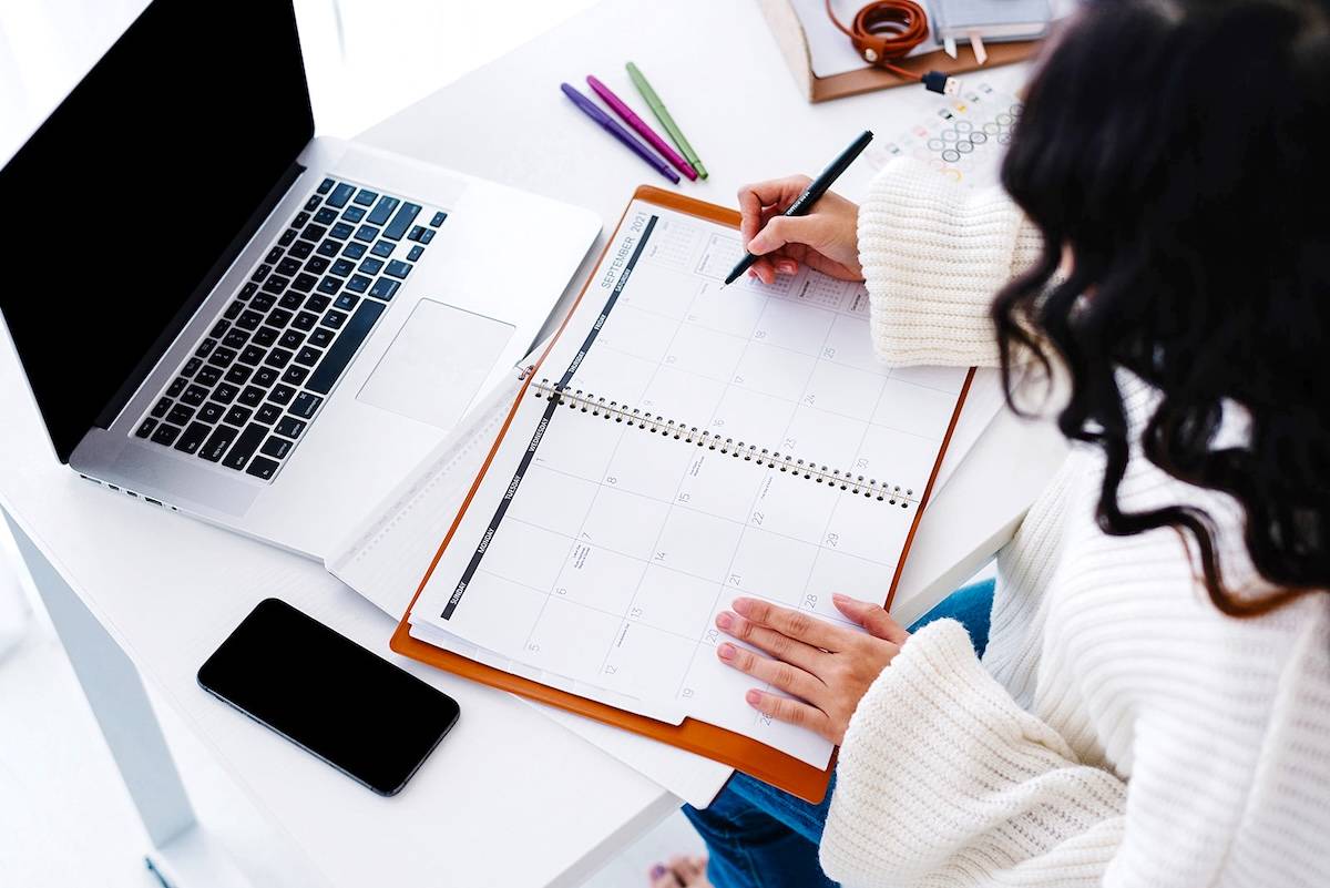 Women writing in a calendar - tips to tackle an overwhelming to-do list.