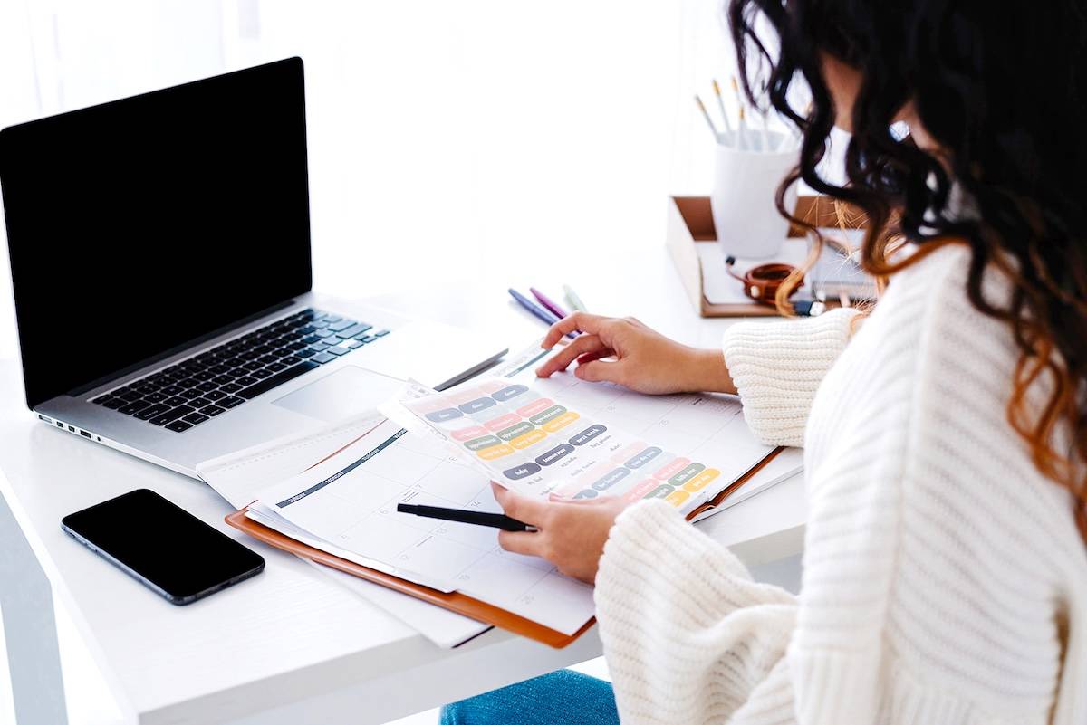 Women placing stickers in a planner - tips to tackle an overwhelming to-do list.